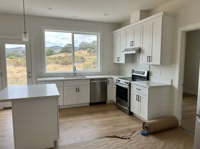 Just-installed white kitchen cabinets and countertops with appliances in place